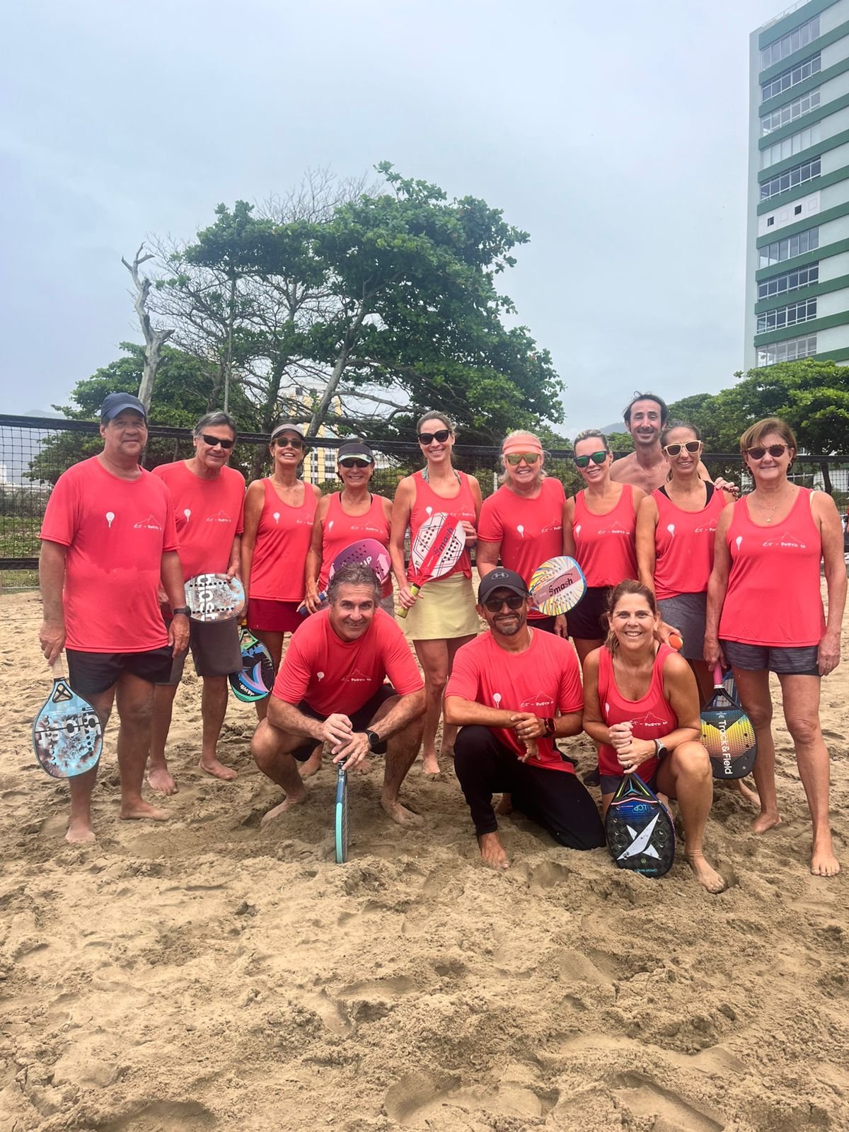 Grupo usando camisetas e regatas personalizadas em atividade esportiva na praia
